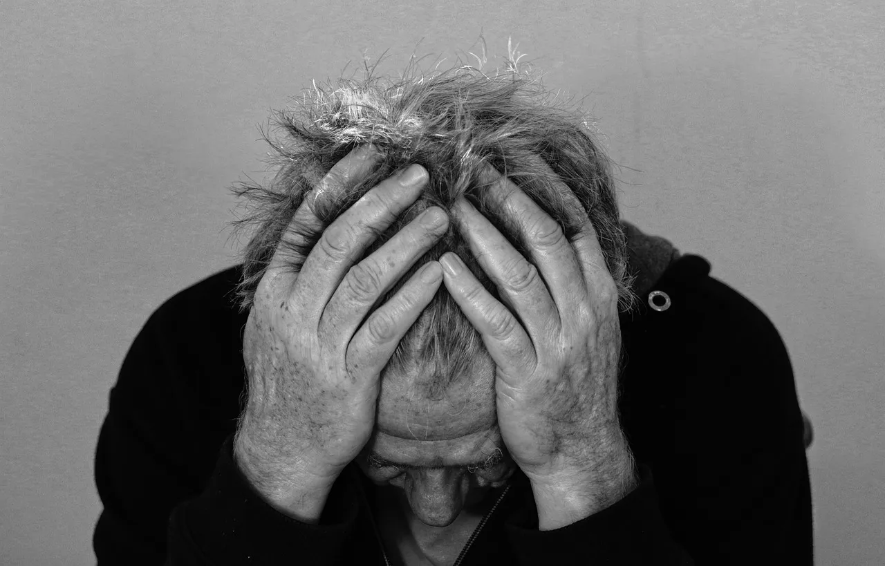 Man holding his head in his hands, overwhelmed by trials and suffering