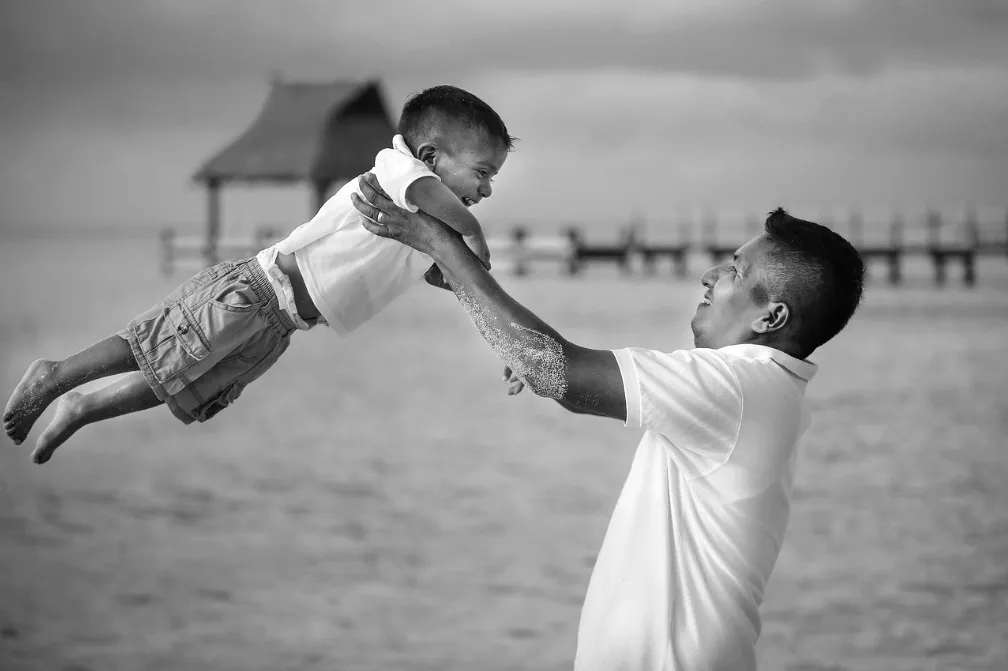 Father lifting his laughing son into the air, picturing faith as trust in a loving Father