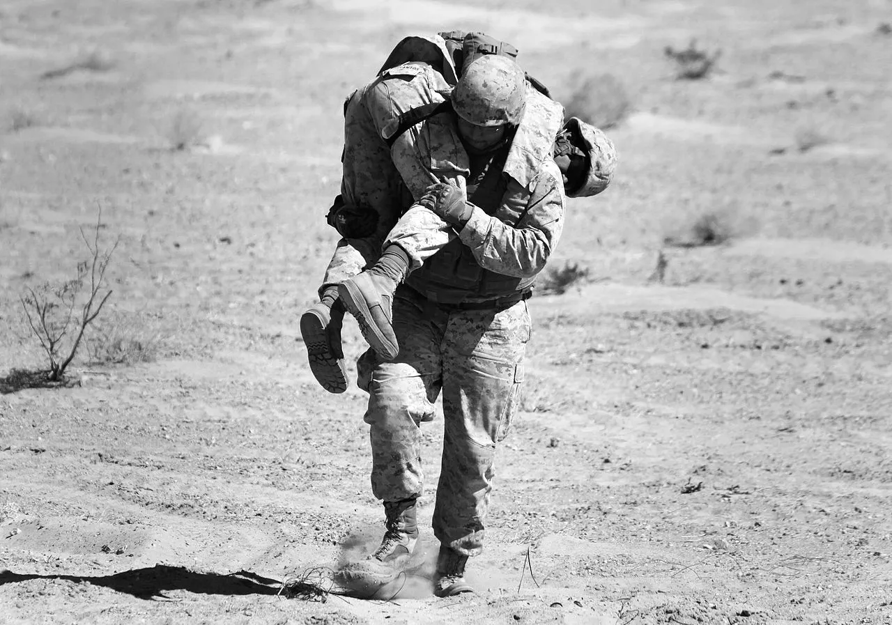 Soldier carrying a wounded comrade, illustrating grace, effort, and the Christian fight against sin