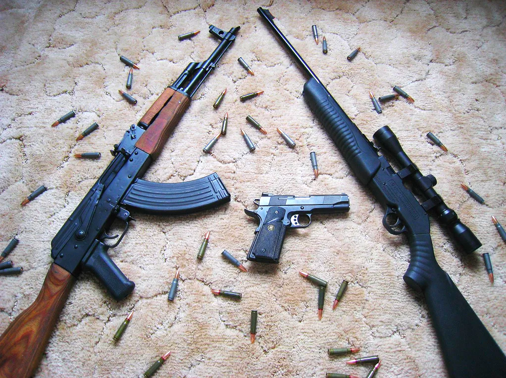 Rifles, a handgun, and ammunition on the floor, for a biblical view of guns and self-defense