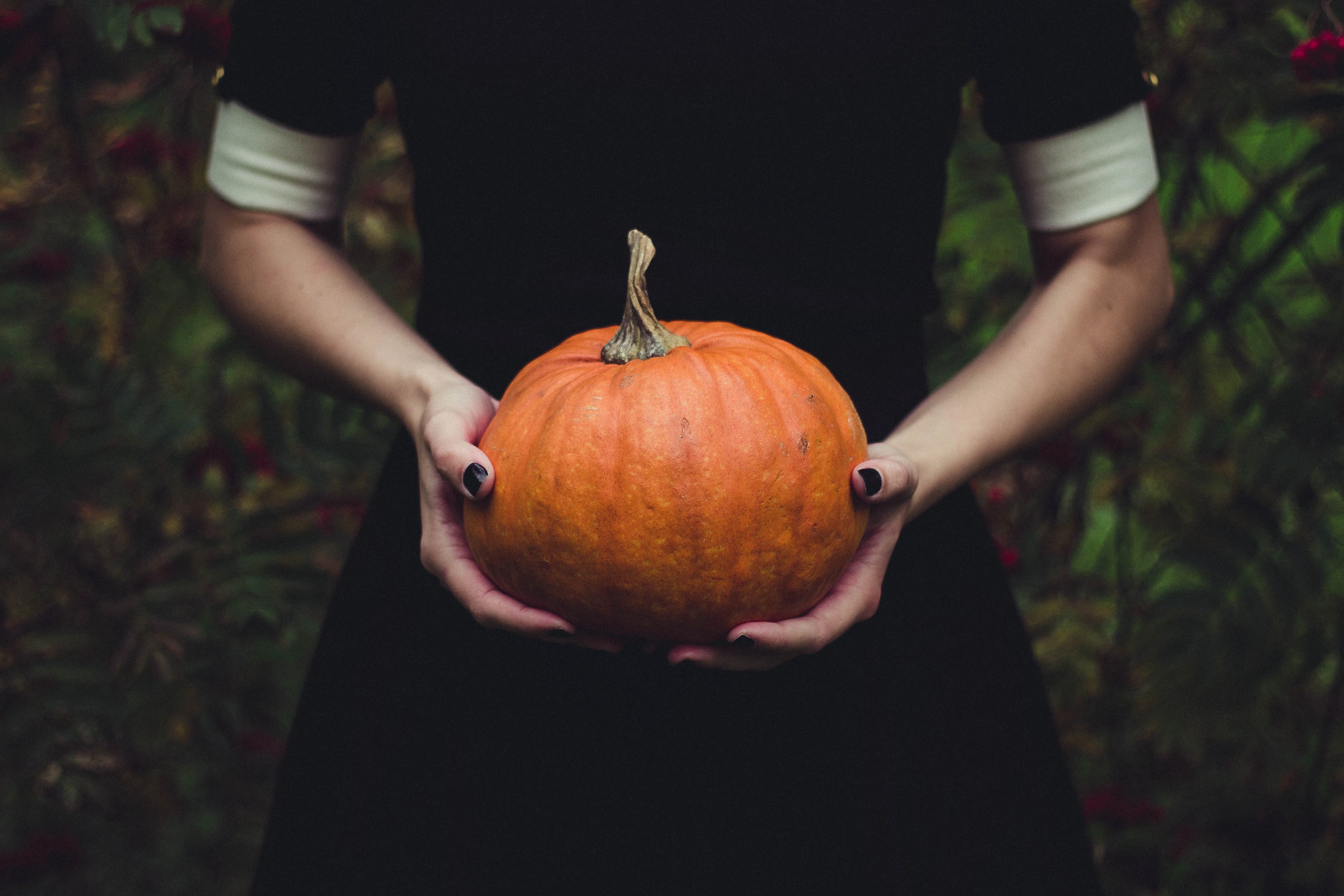 Woman in a black dress holding an orange pumpkin, for a Christian perspective on Halloween