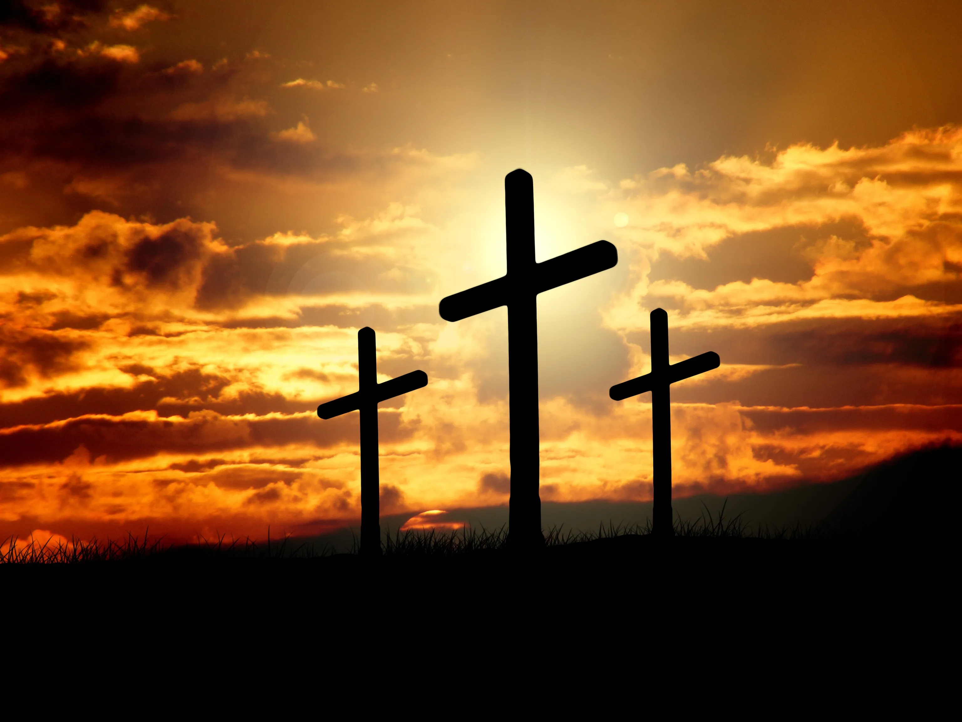 Three crosses silhouetted against a fiery sunset, recalling Christ's forgiveness at Calvary
