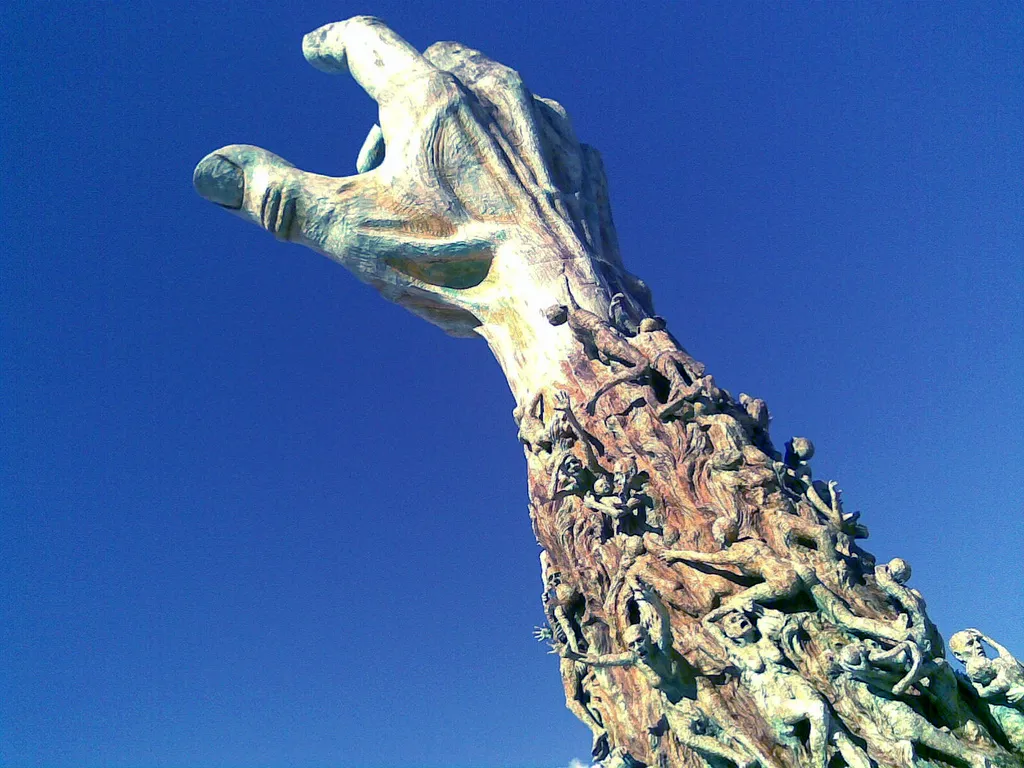 Holocaust memorial sculpture of an outstretched arm covered with suffering figures, for the problem of evil