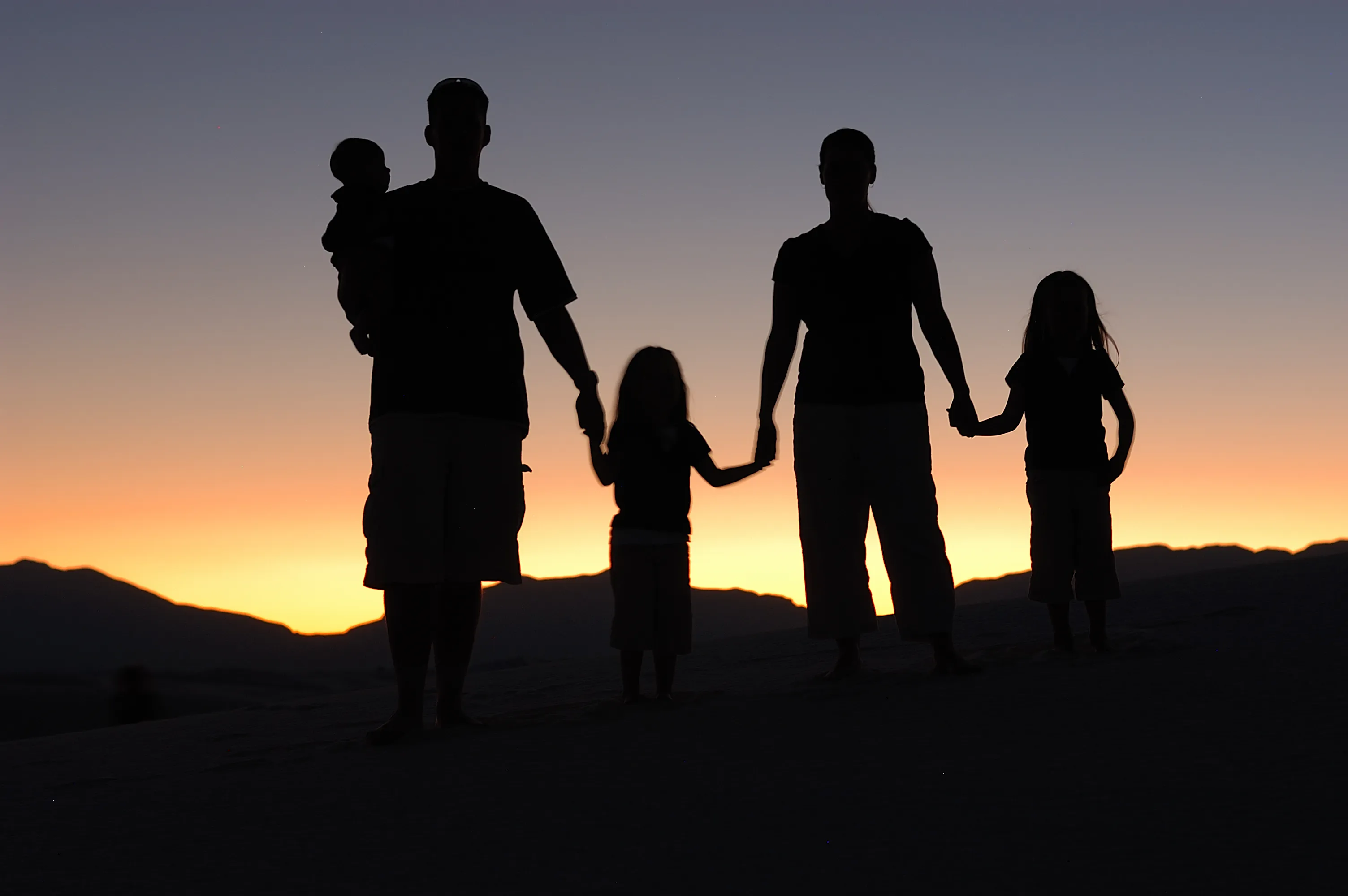 Silhouette of a family holding hands at sunset, illustrating Acts 16:31 and household salvation